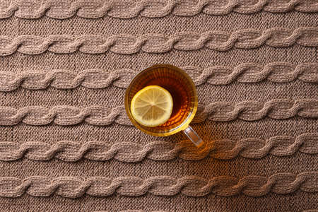 Warming autumn tea with lemon on cozy brown sweater as background. View from above.の写真素材
