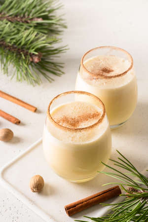 Two holiday Christmas eggnog with grated cinnamon and nutmeg on white. Close up.