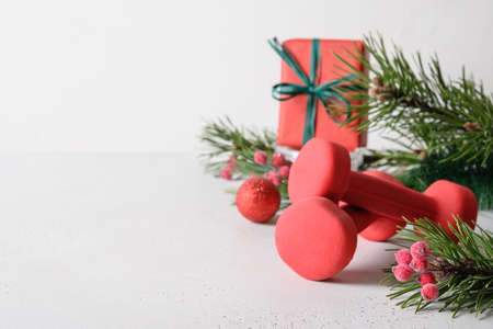 Christmas composition with red dumbbells and gift on white background with copy space. Special offer. Close up. Fitness, sport and healthy lifestyle concept.の写真素材