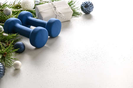Christmas composition with blue dumbbells and gift on white background with copy space. Special offer. Close up. Fitness, sport and healthy lifestyle concept.の写真素材