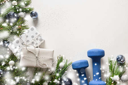 Christmas composition with blue dumbbells, gift, snowy fir branches on white background. Xmas...