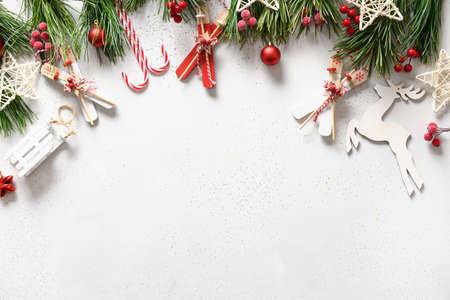 Festive Christmas border with white sleigh, deer, red balls, snowflakes, evergreen branches on white...