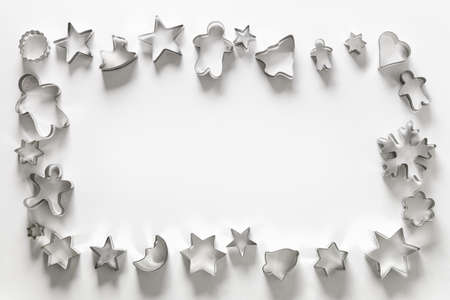 Frame of Christmas-themed cookie cutters on white. Holiday Xmas greeting card. Top view and flat...