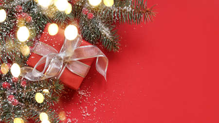 Christmas gift, garland, evergreen branches on red background. Xmas Greeting card with copy space.