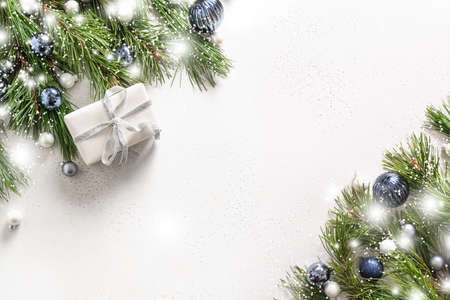Christmas snowy banner with white gift, branches, blue balls on white background with copy space....