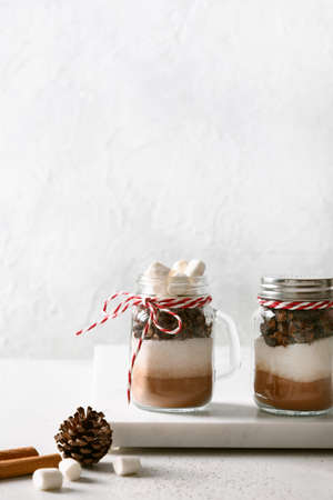 Two homemade edible Christmas gift in glass jar for making chocolate drink on white background. Vertical.の写真素材