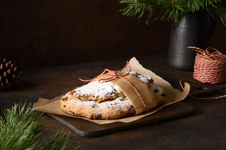 Tasty Christmas stollen decorated holiday rope on brown table. Holiday traditional treats.