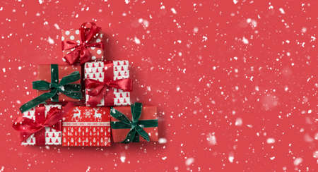Festive red gifts as Christmas tree on red snowy background for greeting card. View from above, flat lay. Template, mockup. Xmas banner for boxing day.の写真素材