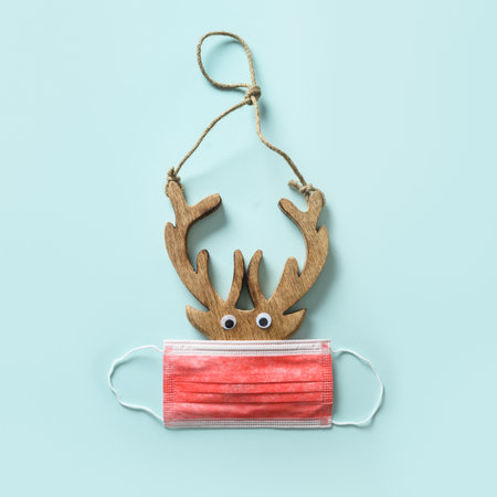 Christmas concept of reindeer with protective medical mask on blue background. Holiday square...