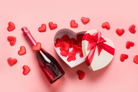 Valentine's Day box in shape of heart and sparkling wine on pink background. View from above. Flat lay. Romantic greeting card.の写真素材