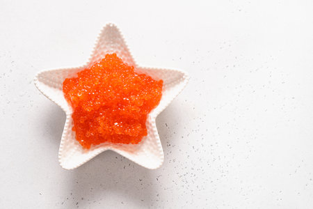 Bowl in shape of star with red caviar on white table. View from above. Space for text.の写真素材