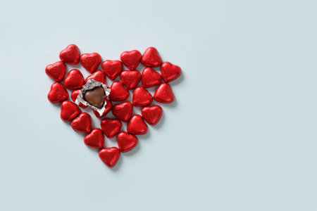 Red chocolate sweets as heart on blue background. Valentines day concept.の写真素材