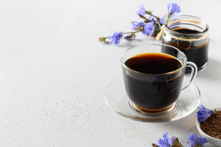 Chicory root coffee in glass cup and fresh flowers. Health Benefits. Copy space. Close up.の写真素材