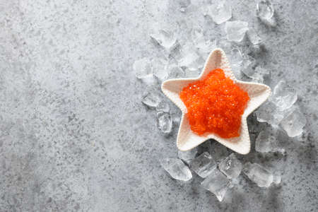 Bowl in shape of star with red caviar on ice on grey stone table. View from above. Space for text.の写真素材