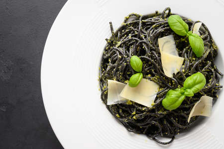 Pasta spaghetti squid Ink with sauce Pesto with fresh basil and parmesan cheese on black background. Top view. Close up.の写真素材