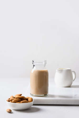 Almond milk in glass bottle and nuts on white background. Close up. Lack of cholesterol.の写真素材
