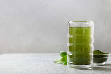Chlorella detox drink in glass and powder in bowl on a grey background. Space for design.の写真素材