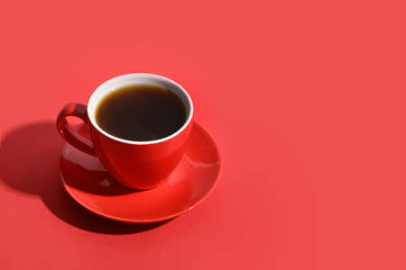 Red cup of coffee on monochrome red background. Copy space. Close up.の写真素材