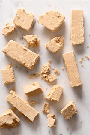 Tasty sweet dessert halva prepared from peanut on white background. Vertical pattern.