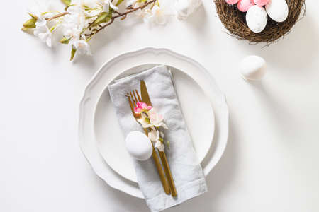 Easter table setting with blooming apple flowers on white table.