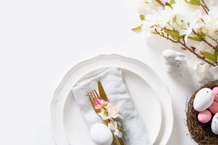 Easter table setting with blooming flowers on white table.