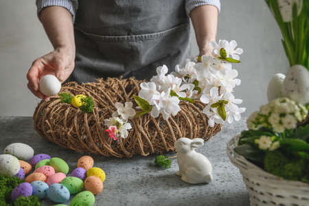 Woman making Easter floral wreath of natural materials of flowers and eggs.の写真素材