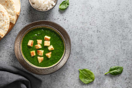 Palak Paneer served with basmati rice on grey. Indian vegetarian cuisine mades of spinach and paneer cheese.の写真素材