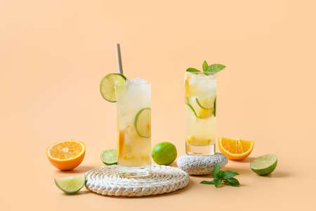 Summer lemonade or cocktail with orange and lime slice on color background. Refreshing drink.の写真素材