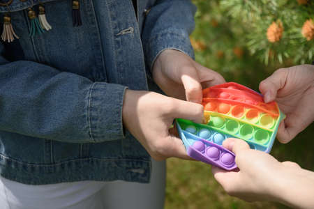 Girls playing in popular silicone anti stress Pop It in hexagon shape toy.の写真素材