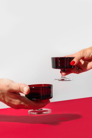 Womans and mans hands with champagne in red glasses for romantic and love party.の写真素材