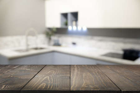 Empty wooden tabletop and defocused modern kitchen as background for design.の写真素材