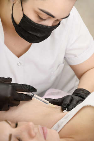 Doctor gives an injection of anesthesia into the armpit before the electrolysis procedureの写真素材