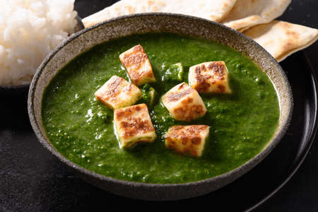Palak paneer of spinach and cheese on black.