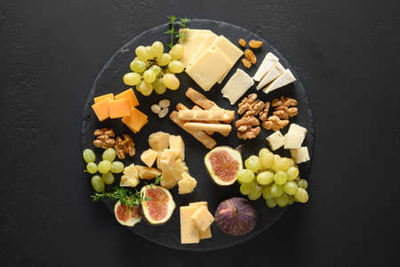 Cheese platter with grapes, nuts, figs on black slate background. Top view.の写真素材