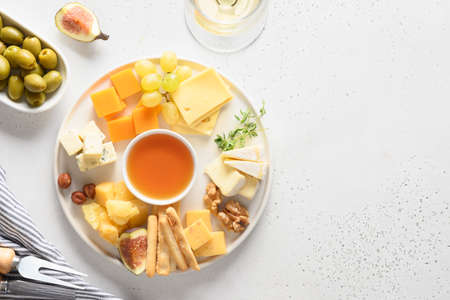 Cheese platter with grapes, nuts, figs on white background. Top view. Copy space.の写真素材