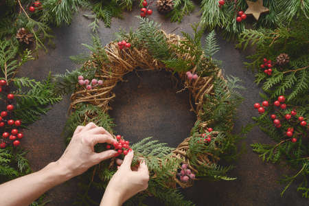 Christmas wreath of fresh natural spruce branch with red berries on brown background. New Year. Xmas holiday.の写真素材