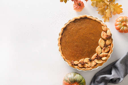 Homemade tasty pumpkin pie with autumn decorations and leaves for Thanksgiving Day on white.の写真素材