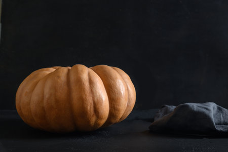 Organic big pumpkin on a black background with Halloween decorations. Autumn harvest for fest.の写真素材