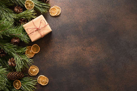 Christmas gift, aroma orange chips, fir tree and cones on brown background.の写真素材