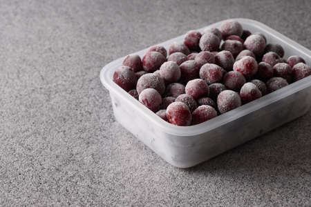 Frozen red sour cherry in container on gray background.の写真素材