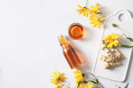 Jerusalem artichoke syrup in bowl, flowers and root.の写真素材
