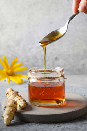 Pouring Jerusalem artichoke syrup in glass jar.の写真素材