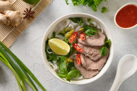 Pho Bo Soup with beef in white bowl on light backgound. Vietnamese cuisine.