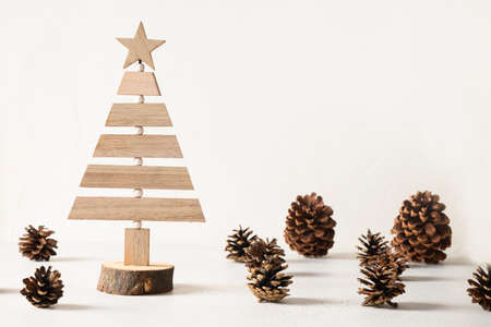 Creative wooden Eco Christmas tree and pine cones on white background. DIY.