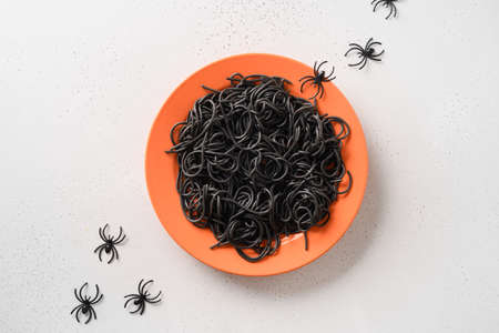 Halloween Italian black pasta decorated funny spiders in orange plate on white.の写真素材