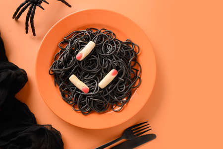 Halloween Italian black pasta decorated funny spiders in orange plate on orange .の写真素材