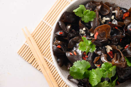 Salad of chinese pickled tree black muer mushrooms in bowl on white background.