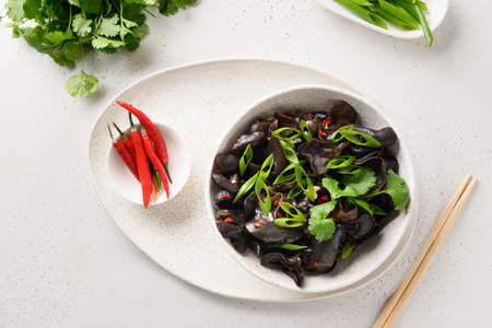 Chinese pickled tree black muer mushrooms with chilli pepper and coriander leaves in bowl.の写真素材