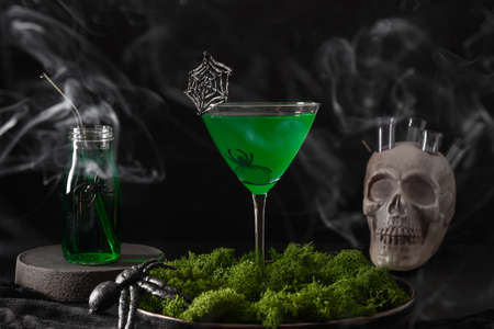 Halloween green cocktails with skulls, spiders and smoke on blackの写真素材