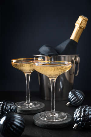 Festive champagne in wine glasses and Christmas blue baubles on dark background. 2022 New Year partyの写真素材